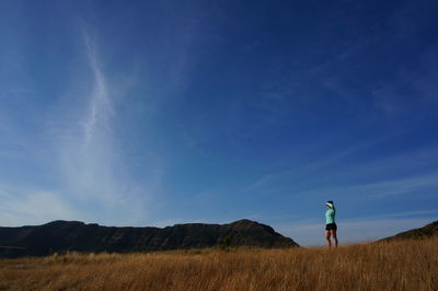 Woman standing on field against sky