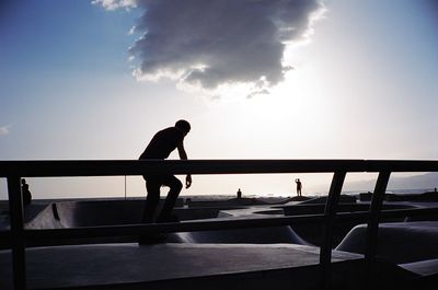 Silhouette man in boat against sky