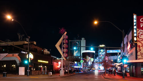 Illuminated city street against sky at night