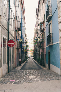 Empty road amidst buildings in city