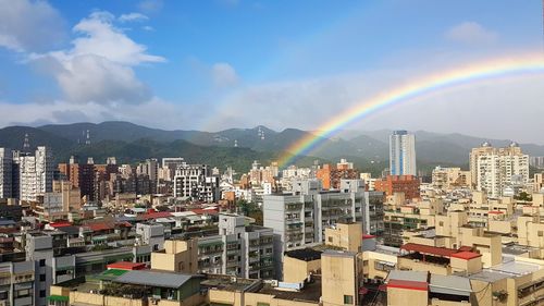 Rainbow over city against sky