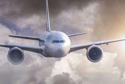 Airplane flying against cloudy sky