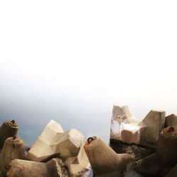 Tetrapods in sea against sky during foggy weather