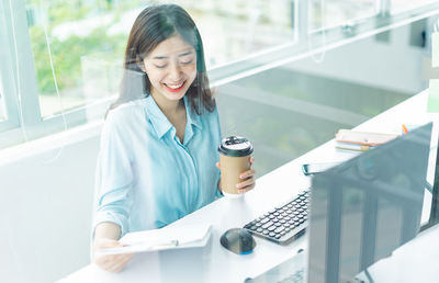 Portrait of young woman using mobile phone in office