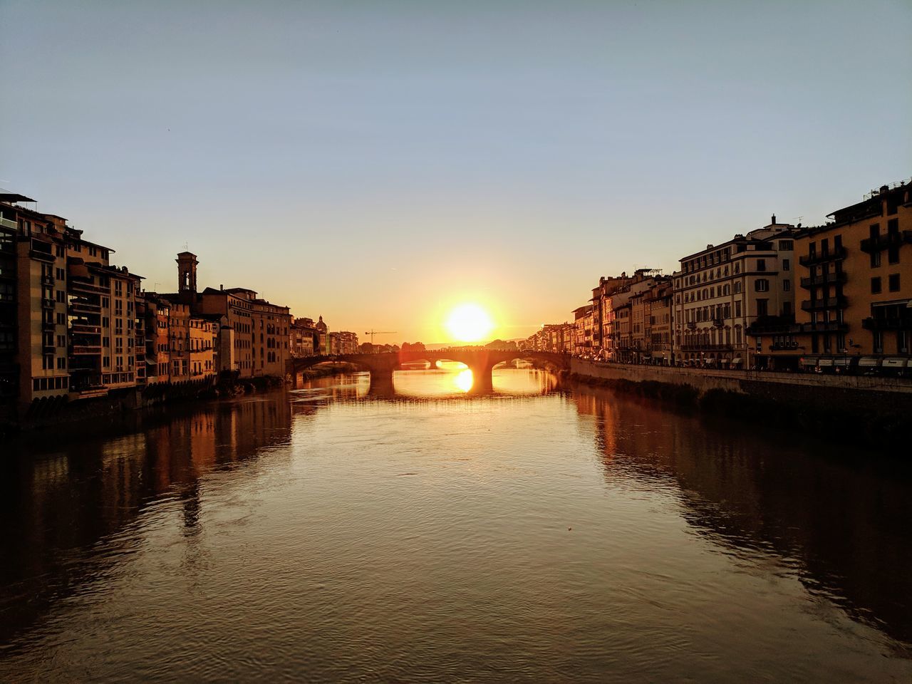 CANAL AMIDST BUILDINGS AGAINST SKY AT SUNSET