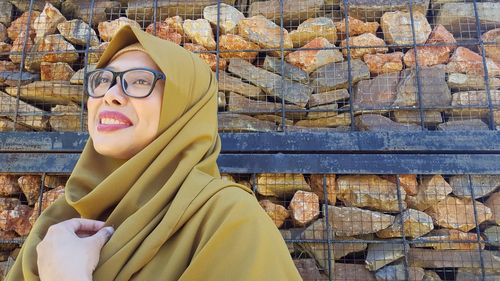 Smiling young woman wearing hijab against stones
