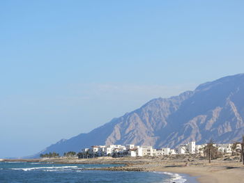 Scenic view of sea and mountains against clear blue sky