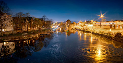 Illuminated bridge over river in city at night