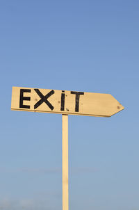 Low angle view of road sign against clear blue sky