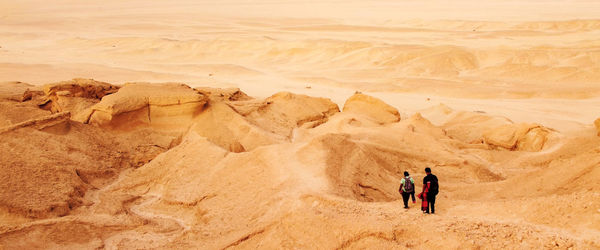 Rear view of men hiking in desert.