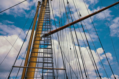 Sailing mast with ropes in front of cloudy blue sky