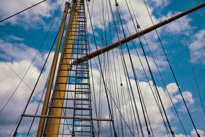 Sailing mast with ropes in front of cloudy blue sky