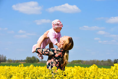 Rear view of women on field against cloudy sky