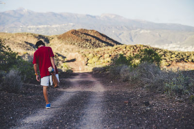 Rear view of man walking on road