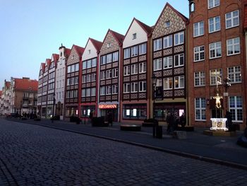Street by buildings against clear sky