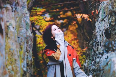 Young woman standing by tree in forest