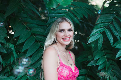 Portrait of smiling woman standing against plants