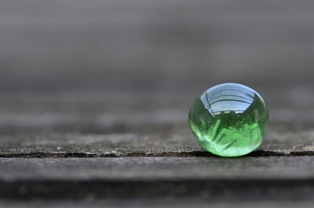 focus on foreground, close-up, selective focus, sphere, green color, glass - material, reflection, transparent, fragility, ball, outdoors, no people, day, bubble, surface level, street, shiny, mid-air, nature, grass