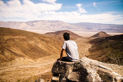 Rear view of a man overlooking rocky landscape