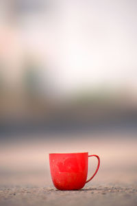 Close-up of coffee cup on table against sky during sunset