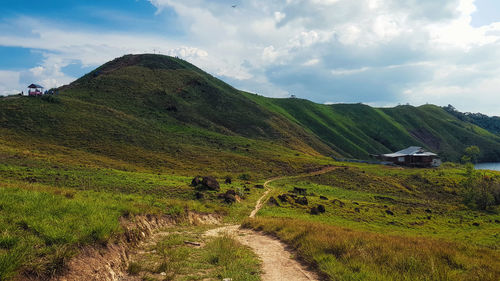 Scenic view of road amidst field against sky