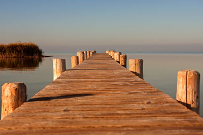 Wooden jetty on pier in sea against clear sky