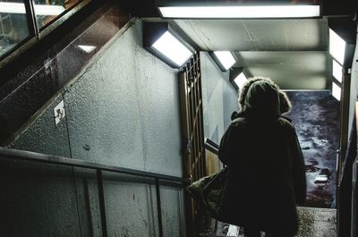 Rear view of person walking on steps in building