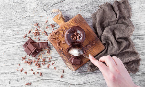 Cropped hand of woman taking chocolate at wooden table