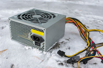 A computer power supply lies in a landfill in the snow