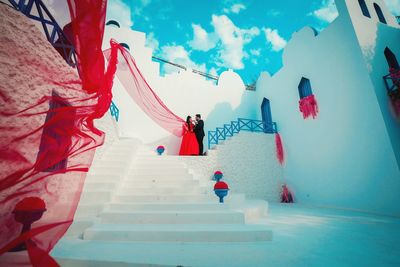 People relaxing on staircase against sky