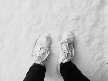 Low section of person standing on snow covered land