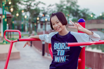 Cute girl playing with arms raised standing outdoors