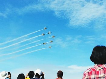 Rear view of tourists watching display team in aerobatic air show