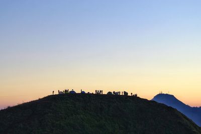 Silhouette people on mountain against clear sky during sunset