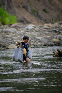 Woman carrying sticks while walking in river