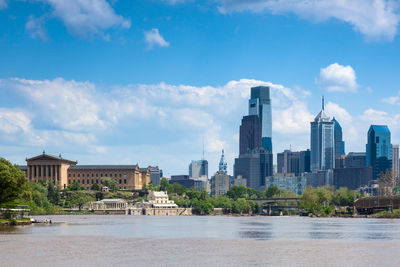 Modern buildings by river against sky in city