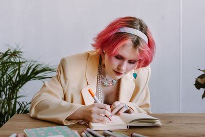 Young woman wearing blazer drawing on book