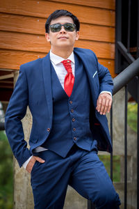 Portrait of bridegroom wearing sunglasses standing by railing