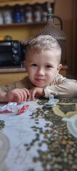 Portrait of boy playing with candy on table