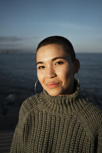 Smiling woman staring while sitting against sky