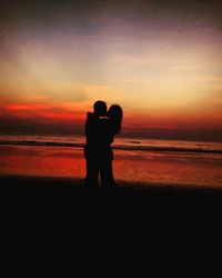 Silhouette men standing on beach against romantic sky