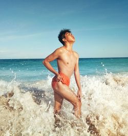 Rear view of shirtless man swimming in sea against sky