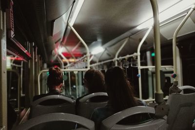 Rear view of women traveling in bus at night