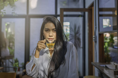 Portrait of young woman drinking drink