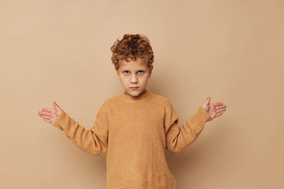 Portrait of boy standing against yellow background