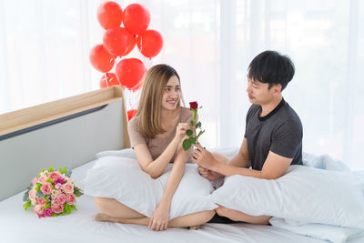 Women sitting on bed by potted plant