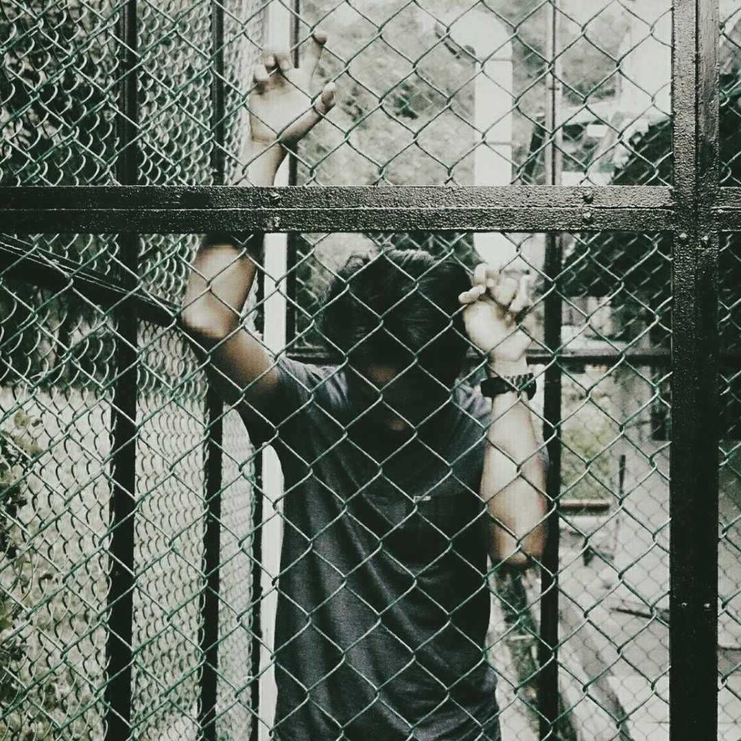 PERSON SEEN THROUGH CHAINLINK FENCE