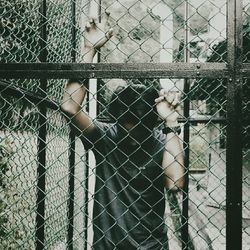Man seen through chainlink fence in cage