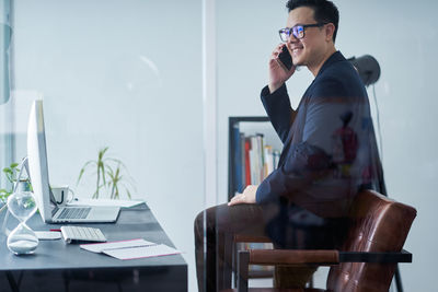 Young man using mobile phone while sitting on table