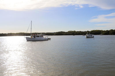 Boats sailing on river against sky